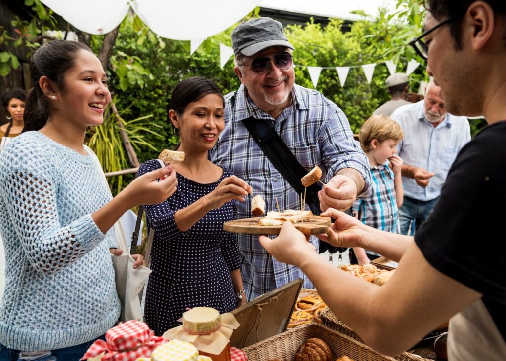 Imagem mostra pessoas felizes degustando queijo no festival do queijo em Serro, Minas Gerais.