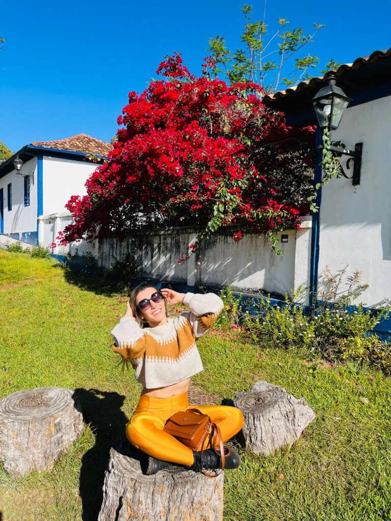 Imagem mostra jovem feliz tirando foto em vila aconchegante de Diamantina.