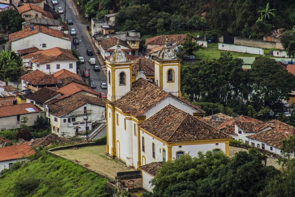 Imagem mostra igrejinha e rua movimentada em Ouro Preto, uma das principais cidades da Estrada Real Minas Gerais.